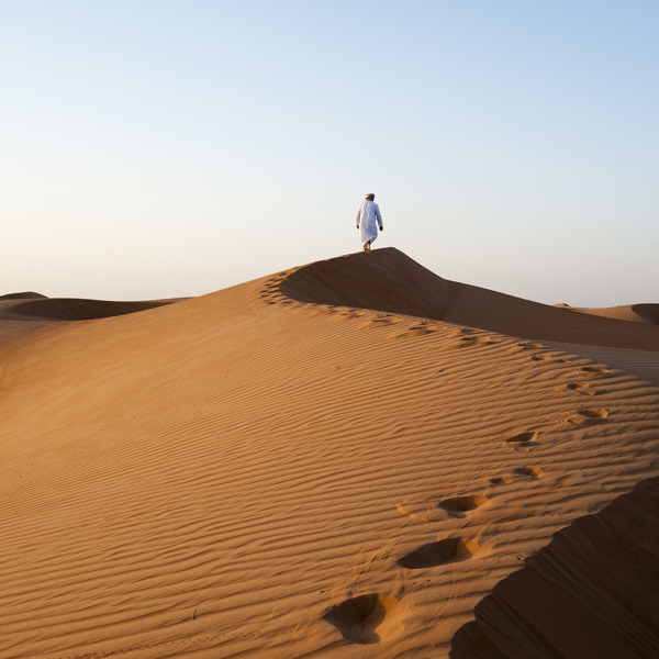 Omani mand der går i Wahiba Sands ørkenen i Oman