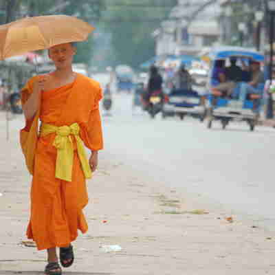 Munk med paraply på gaden i Luang Prabang